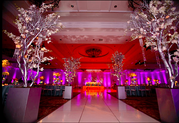 Silver branches filled with lights and blooms reflect the pink light for a magical setting Image provided by The Finishing Touch Event Design